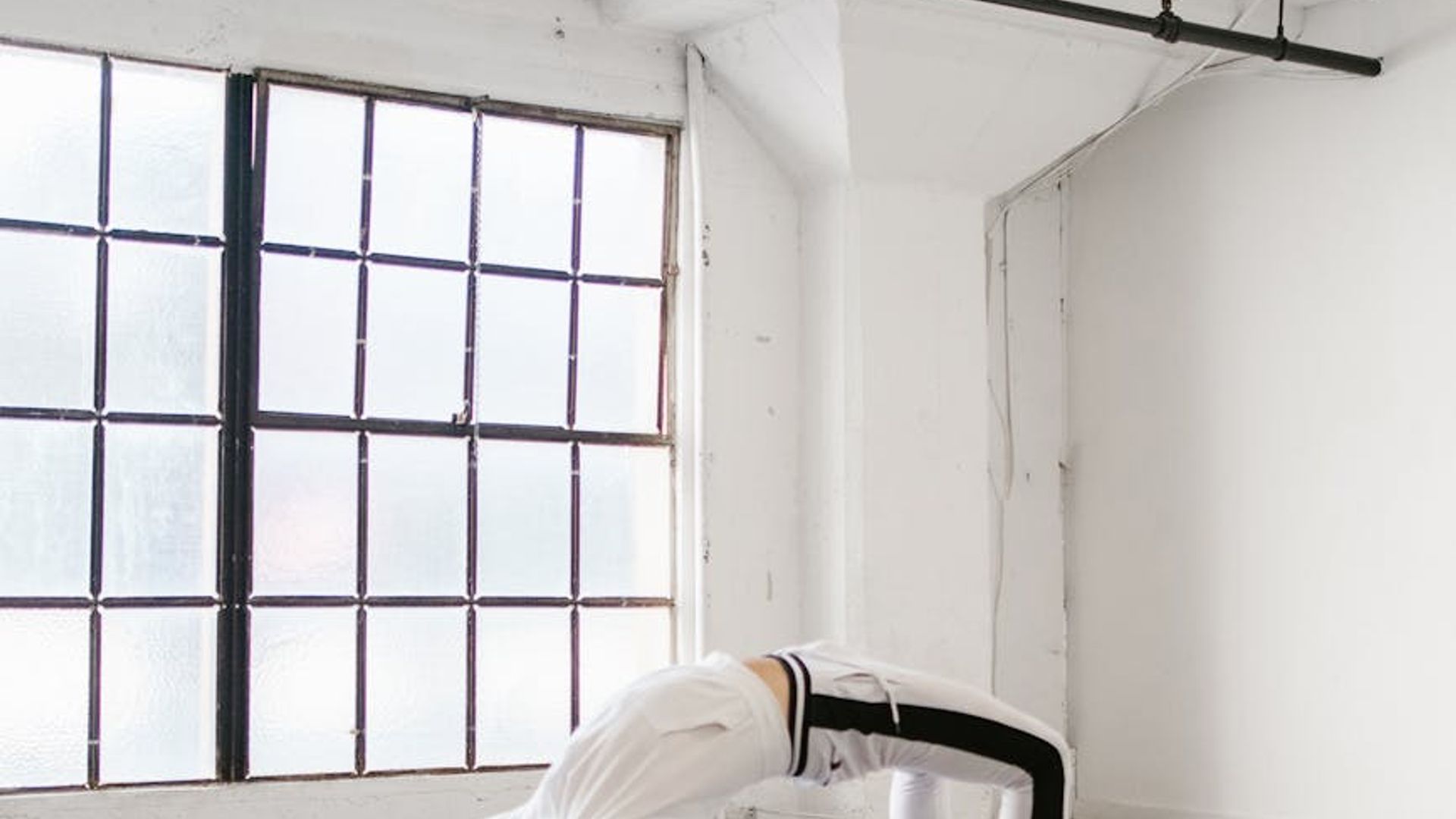 Person practicing yoga in a bright minimal studio space.